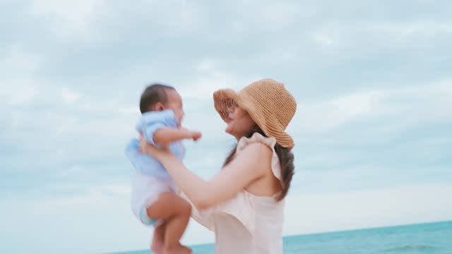 Sky-High Joy with Baby a joyous mother in a straw hat lifts her baby up high, celebrating a moment of pure happiness.
