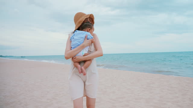 Mother Holding Baby walking on Beach, Serene Ocean vacation