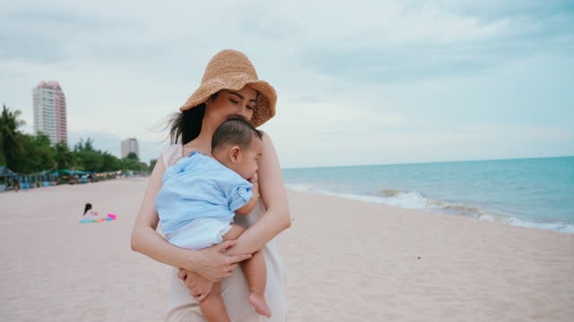 Mother Holding Baby walking on Beach, Serene Ocean vacation