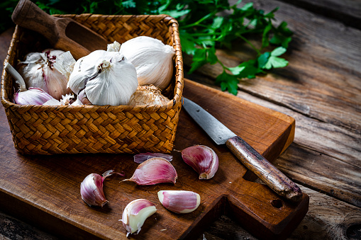 Garlic bulb and cloves on wooden cutting board