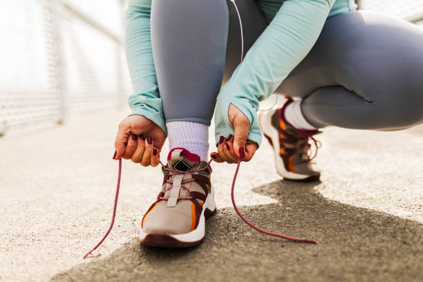 istock Woman Pausing to Tie Shoelaces 2102326599