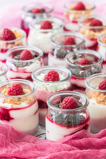 Fruity quark dessert with raspberries and chocolate or crisp topping in small glasses