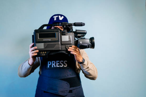 istock Reporter in bulletproof vest holding a video camera 2102328690