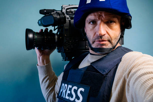 istock Reporter in bulletproof vest holding a video camera 2102329207