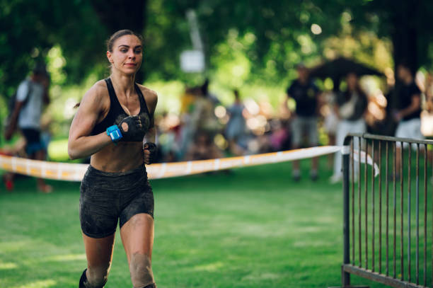 Woman athlete partake in one of the events of an obstacle course race while running to the finish line. Female working out outside. Sport competition and OCR race. Copy space.