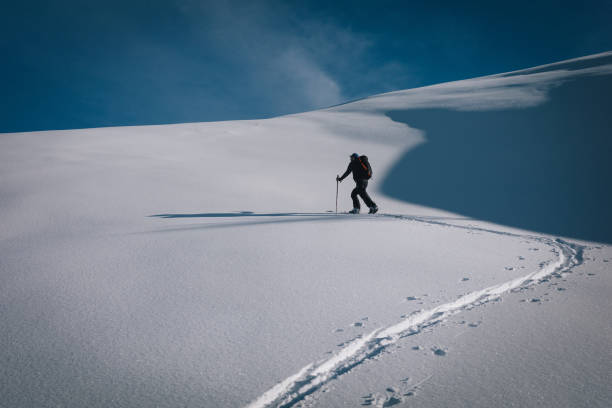 istock Backcountry snowboarder ascends mountain 2102353302