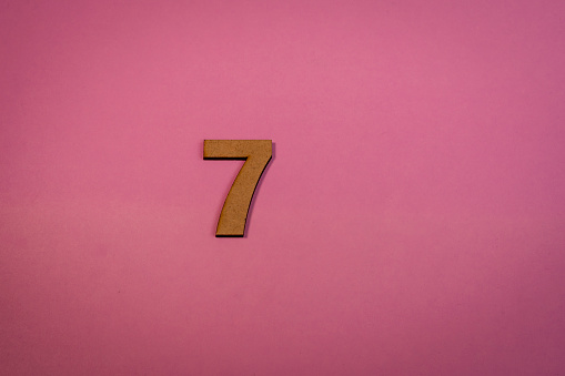Number 7 in wood on a pink background