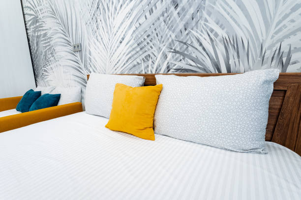 istock Bed with white linens and yellow pillows on azure floor 2102354464