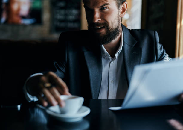 istock business man sitting at a table in a cafe documents work official coffee cup 2102355561