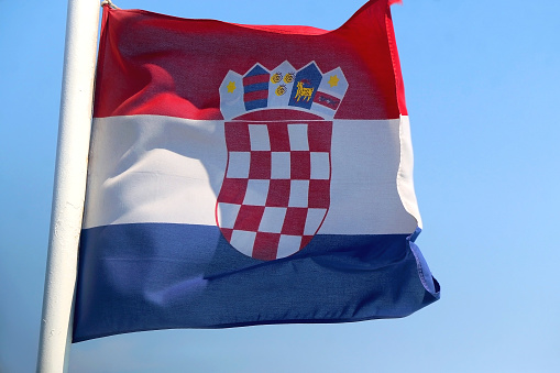 Flag of Croatia, blowing in the wind. Bright blue sky in the background. Selective focus.