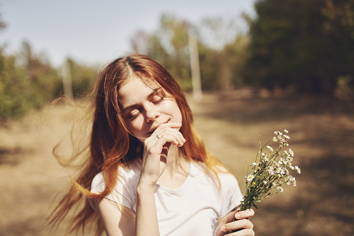 happy woman in a field with a bouquet of white flowers in nature. High quality photo