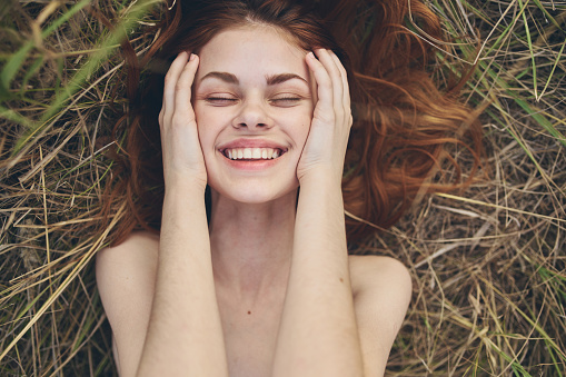 happy woman on dry grass laughs in nature. High quality photo