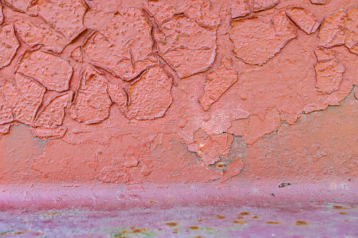 Large old red damaged peeling paint. Old weathered painted wall background texture.