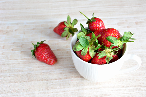 a white mug with strawberries isolated on the tanle top view