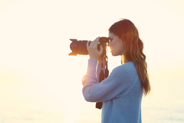 istock Woman with camera landscape sunset sea sun model 2102404848