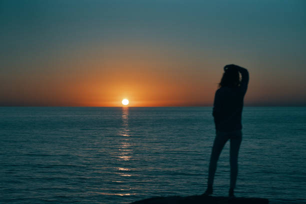 istock woman gesturing with her hands and sunset sea landscape beach 2102405368