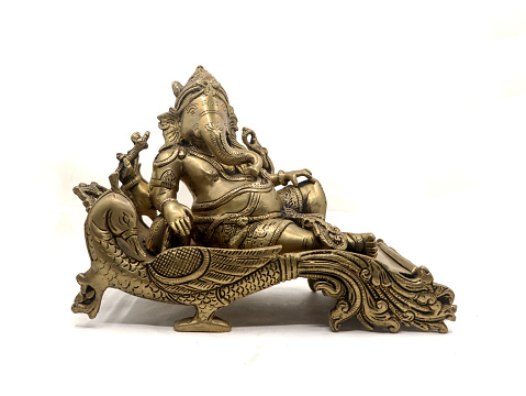 antique golden statue of elephant headed god lord ganesh sitting on a peacock throne isolated in a white background