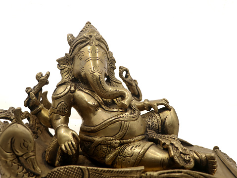 closeup shot of ornate lord ganesh statue from hindu mythology carved in golden brass metal isolated in a white background