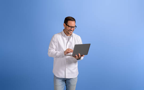 istock Portrait of handsome entrepreneur checking e-mails over wireless computer on blue background 2102422887