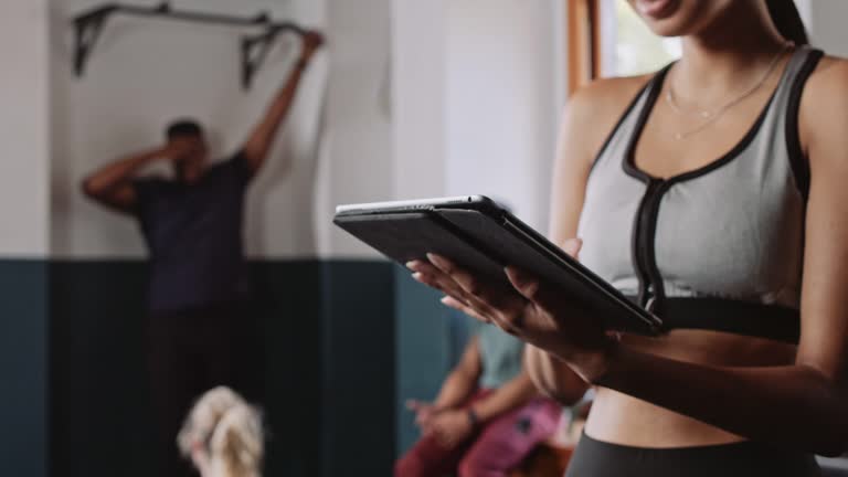 Medium shot of female fitness trainer using tablet in fitness studio