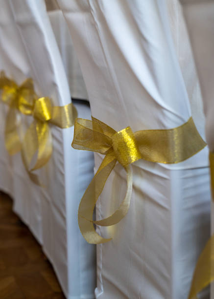 Chair covered in white fabric with orange striped decorations for event purposes. Wedding events.