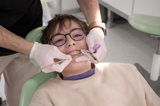 Boy having orthodontic examination in dentist's chair. Perfect for dental clinics and healthcare promotions.