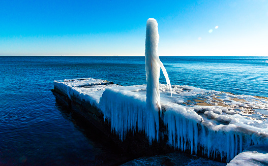 Icing of a concrete pier in the Black Sea, blocks of melted ice glisten in the sun, ice by the sea, Odessa