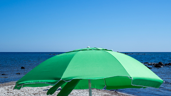 Green beach umbrellas. Blue sky. Relaxing context. Summer holidays at the sea. General contest and location