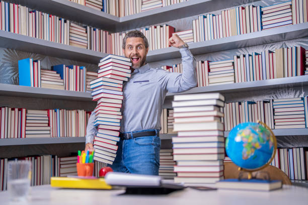 istock Knowledge and education. school library. Teachers day. Teacher in school classroom. teacher with book in library classroom. Hispanic teacher in college. Man with books in library. power of reading 2102511111