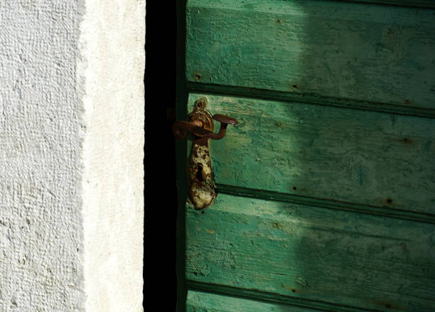 Old wooden half-open door with a rusty vintage brown doorknob