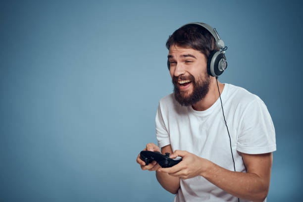 istock Man in headphones controller in hands playing game console lifestyle emotions blue background white t-shirt 2102537195