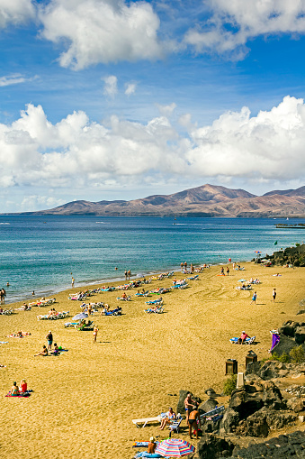 View along the beach in Playa Blanca, Lanzarote, Spain.  People can be seen ion the beach
