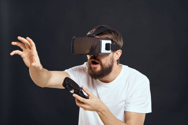 istock man wearing virtual reality glasses with gamepad in hand technology games leisure dark background 2102546165