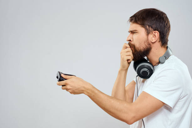 istock Man with gamepad headphones playing leisure technology white t-shirt light background 2102555769