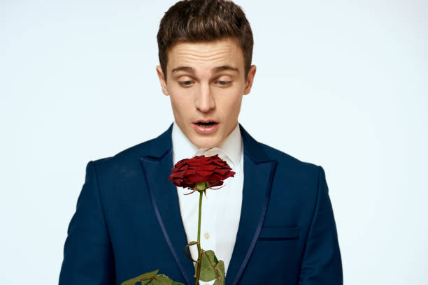 A man in a suit with a rose in his hands a gift date light background. High quality photo