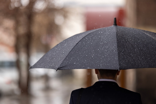 Portrait of businessman in rain in city