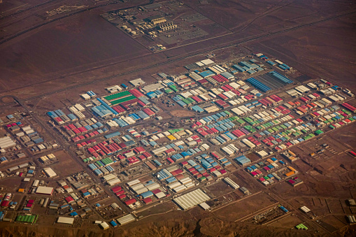 Aerial shot of the industrial district of Tehran, colorful factory roofs viewed from the airplane window