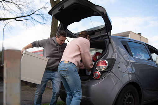 Women unpack things from the car and help with the move
