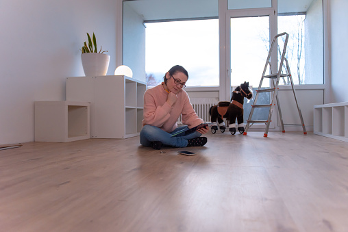 Happy woman planning home repairs and moving while sitting on floor in living room