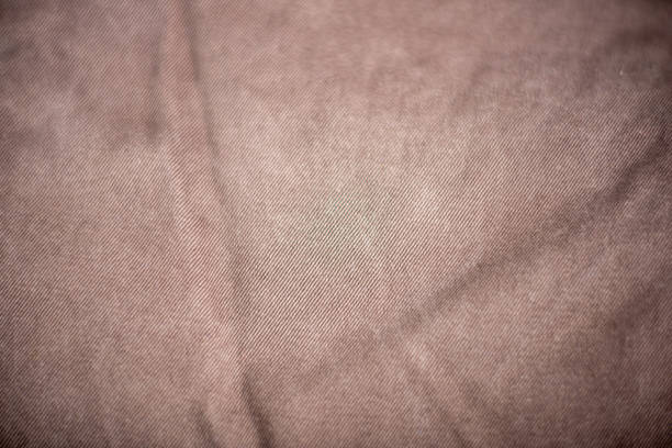 A close up of a tan fabric with a pattern. The fabric is wrinkled and has a worn look to it