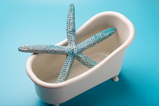 A starfish is in a bathtub. The bathtub is white and blue