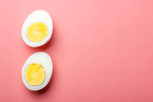 istock Two eggs are cut in half and placed on a pink background 2102691463