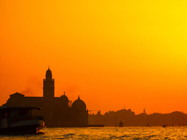 Venice, Italy. 29 october 2022. silhouettes of Venice at sunset in the bright warm orange-red rays of the setting sun. view from the water