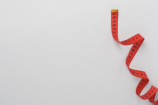 Measuring tape on color background, top, view