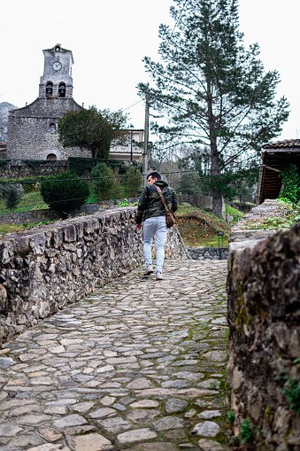 Stone bridge in Cabrales village, with quaint chapel amid lush greenery visited by wandering tourist