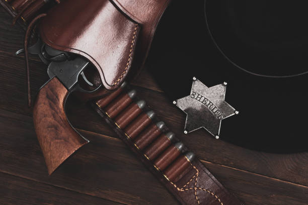 istock Sheriff star with gun, holster and gun belt with old west hat on table. Top view. 2102882629