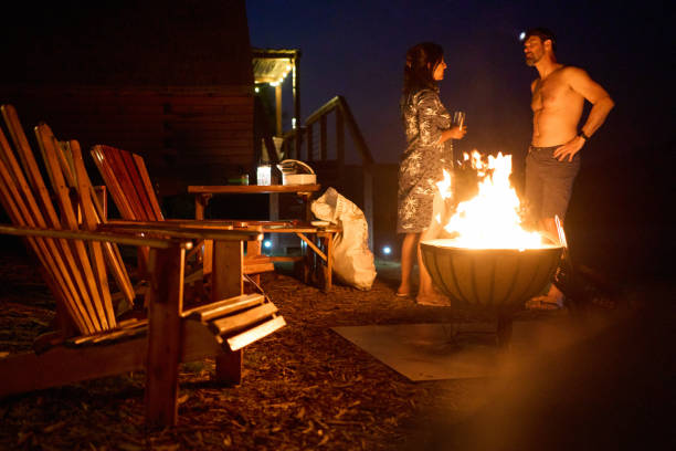 istock Smiling friends relaxing around a cabin campfire at night during a vacation 2102926424
