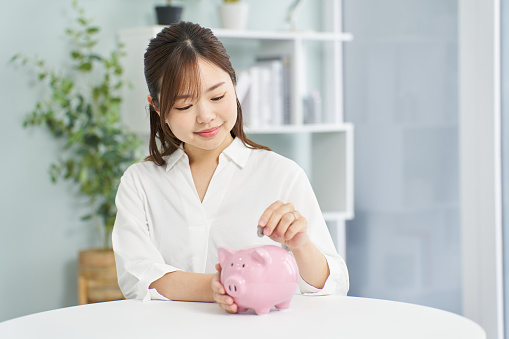 A woman putting money into a pig piggy bank
