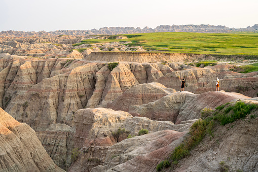 Interior, USA - June 14, 2023. Man looking at scenery while lady taking pictures at Badlands National Park, South Dakota, USA