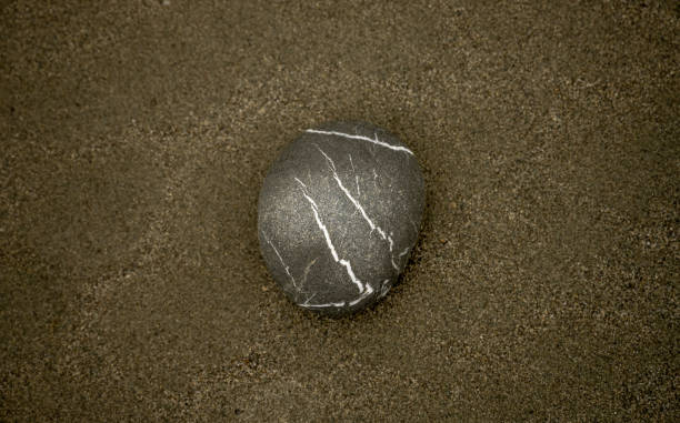 istock Single Rock With White Veins Sits On Sandy Beach 2102941467
